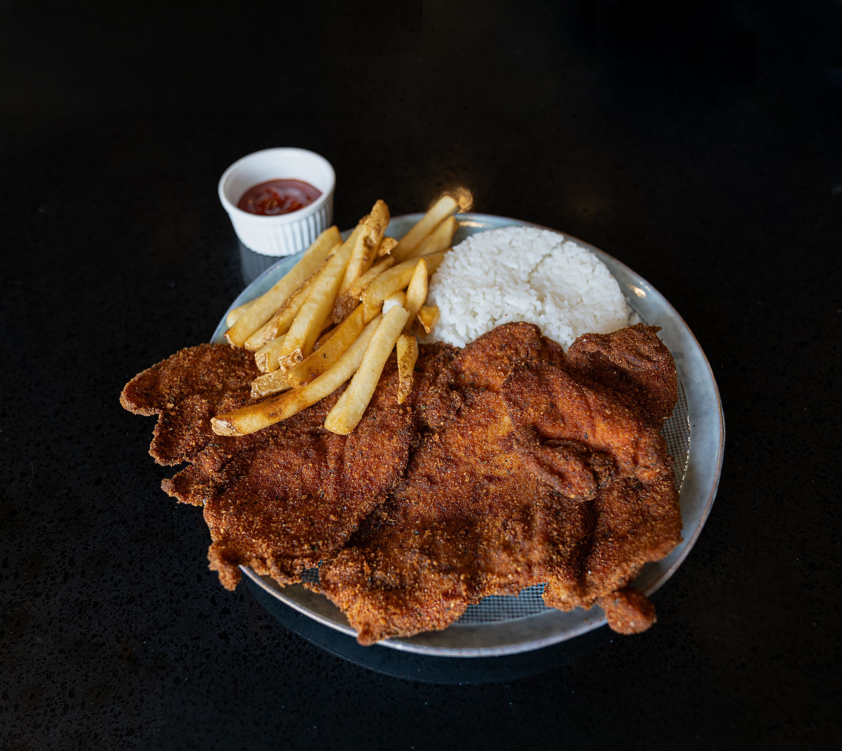 Chuleta de Pollo Breaded and fried chicken breast served with rice and fries.