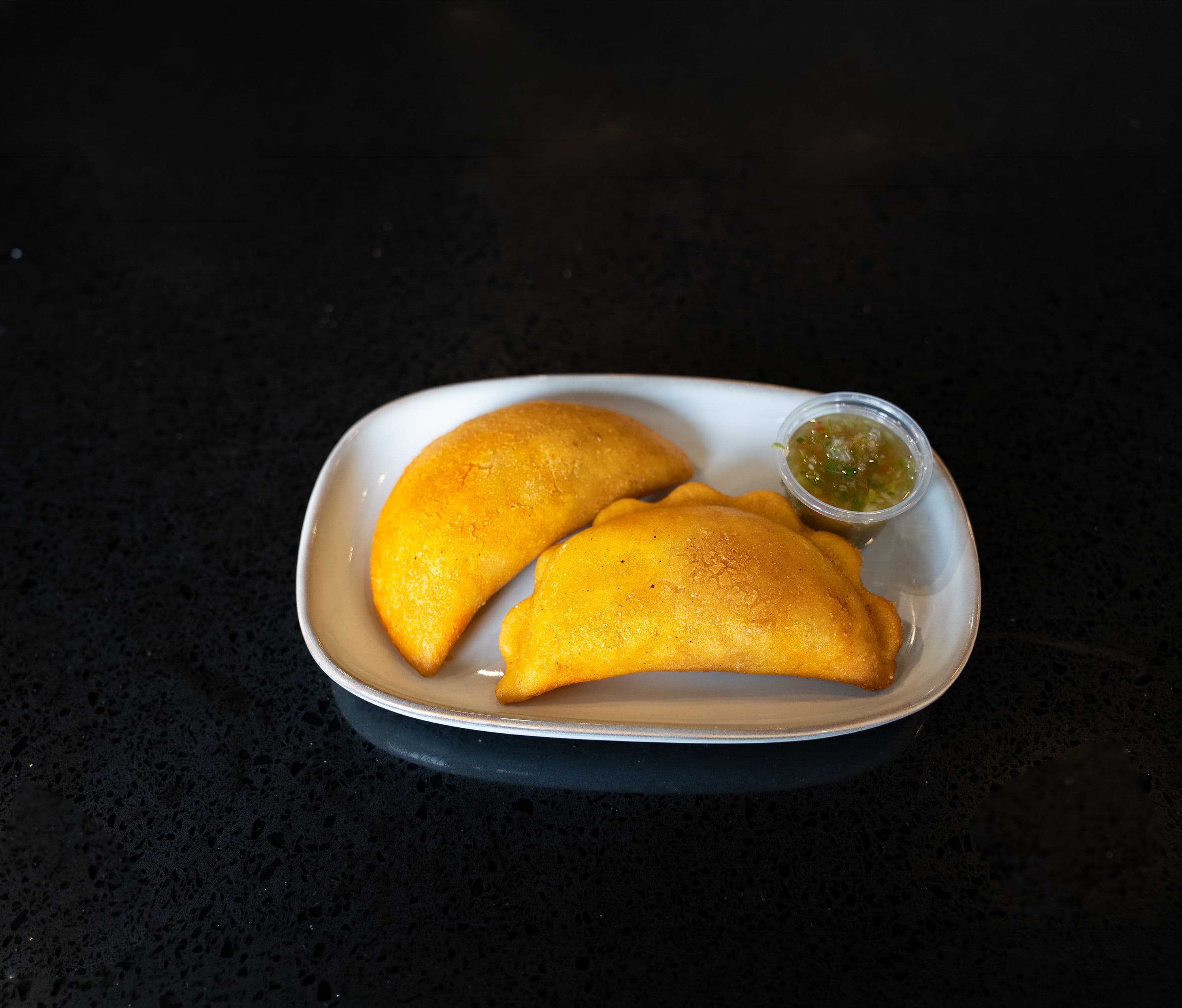 Colombian Empanadas Crispy corn empanadas filled with seasoned beef and potato, served with traditional ají.